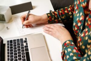 female hand writing by pen. Unrecognizable elegant woman working on computer at office. Start or fin